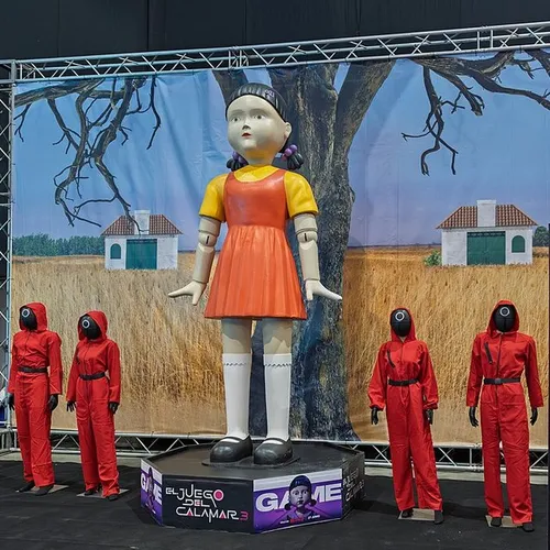 La poupée géante de Squid Game entourée de gardes en combinaison rouge